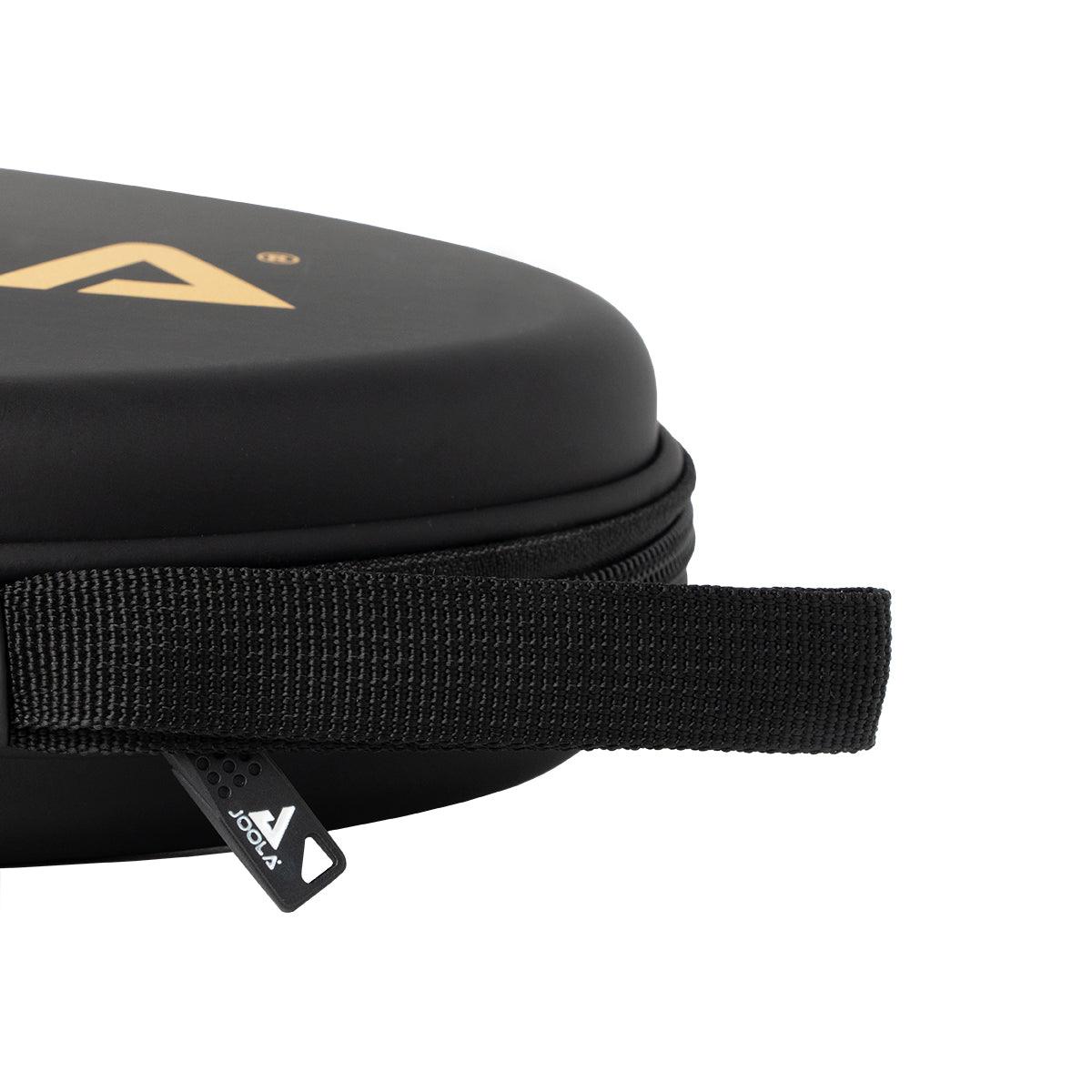 Schwarze, runde Hartschalen-Tasche mit Reißverschluss und Trageschlaufe, Detailansicht.